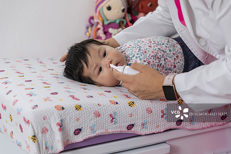 儿科医生给婴儿用鼻腔减充血剂图片素材