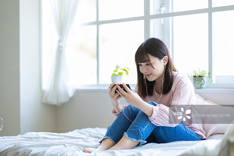 在床上看智能手机的女人图片素材