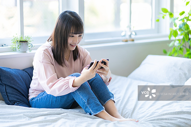 在床上看智能手机的女人图片素材