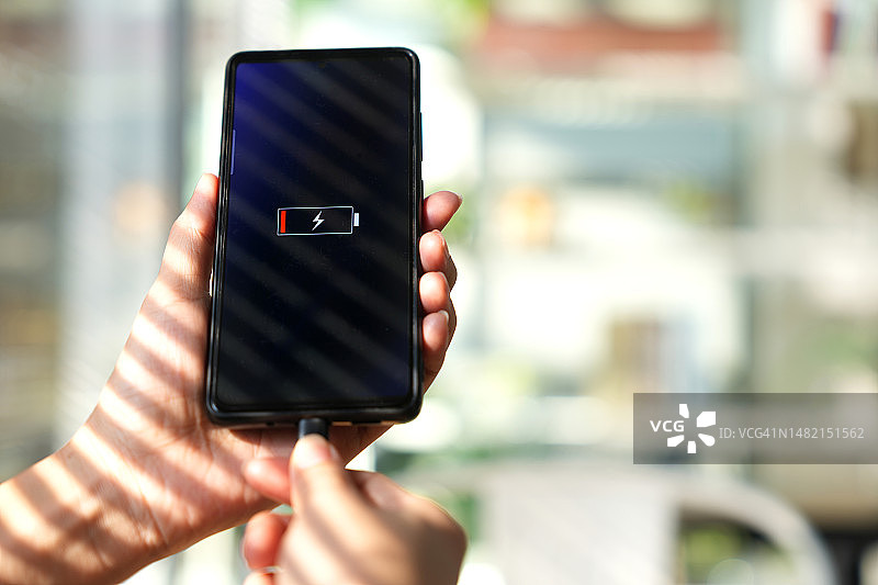 女人在咖啡馆手持低电量手机充电图片素材