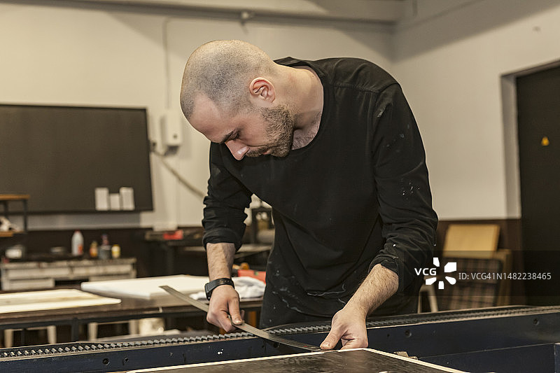 艺术家用金属尺测量石印机中的距离图片素材