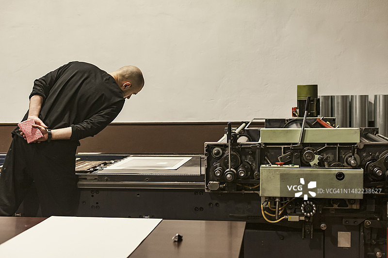 一位正在查看石印机或滚压机上的纸模或模板的艺术家图片素材