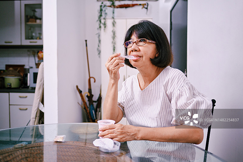 年长的妇女在客厅吃酸奶图片素材