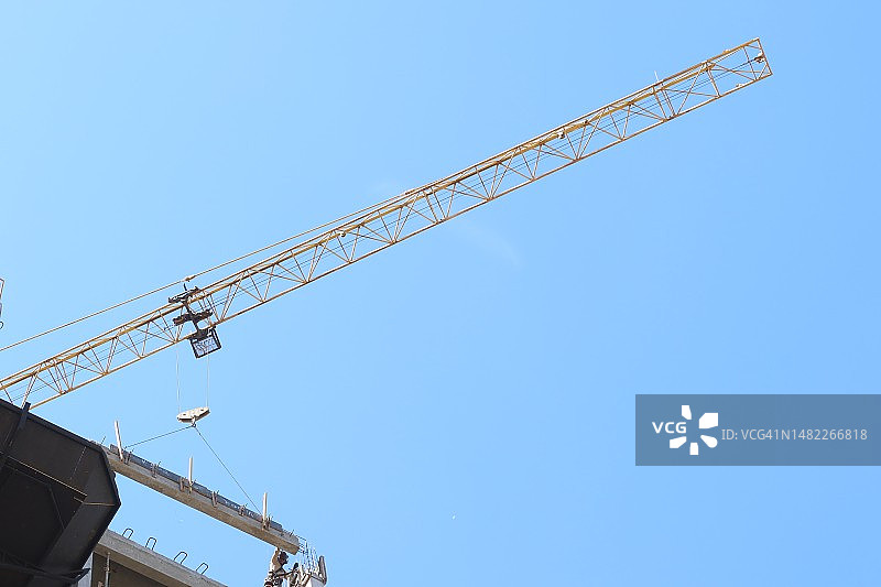 起重机吊起柱子，建筑工人协助的高空景象图片素材
