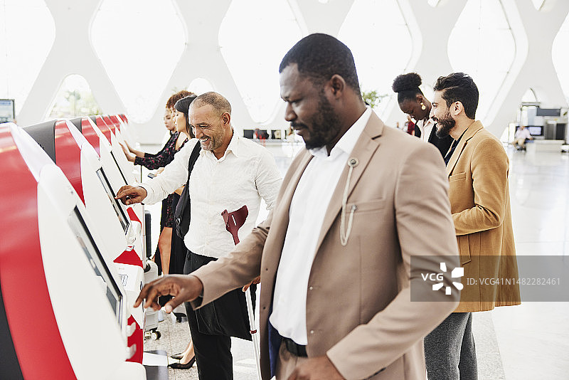 残疾男子在机场自助服务亭办理登机手续的广角镜头图片素材