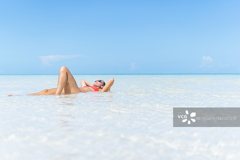 穿比基尼的女人在白色沙滩上享受日光浴图片素材
