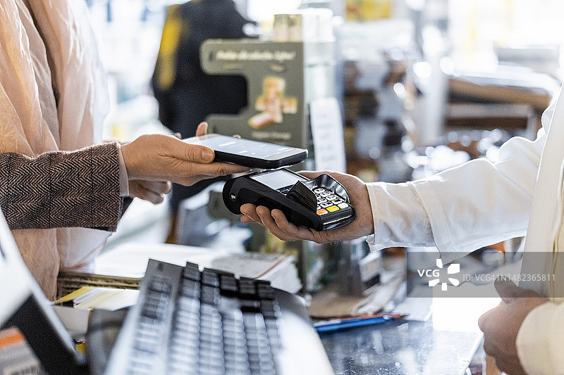 顾客在药房通过智能手机进行非接触式支付图片素材