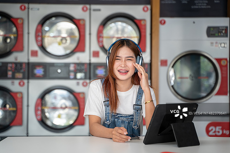在洗衣店等待洗衣机工作的亚洲女性图片素材