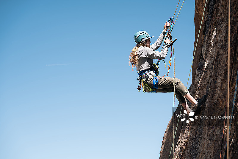一位年轻女士仅用两只手攀爬绳索图片素材