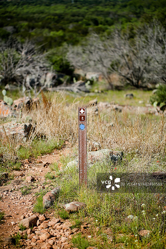 德克萨斯州大理石瀑布墨湖州立公园 - 远足小径上的小径标记，背景中有小径和绿色图片素材