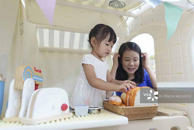 快乐情绪：亚洲女婴和母亲一起玩角色扮演游戏，制作冰淇淋图片素材