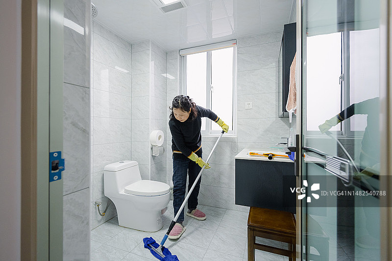 中年家庭主妇在擦拭浴室地板图片素材