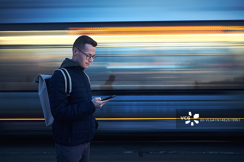 男子在电车前使用手机（虚化运动效果）图片素材