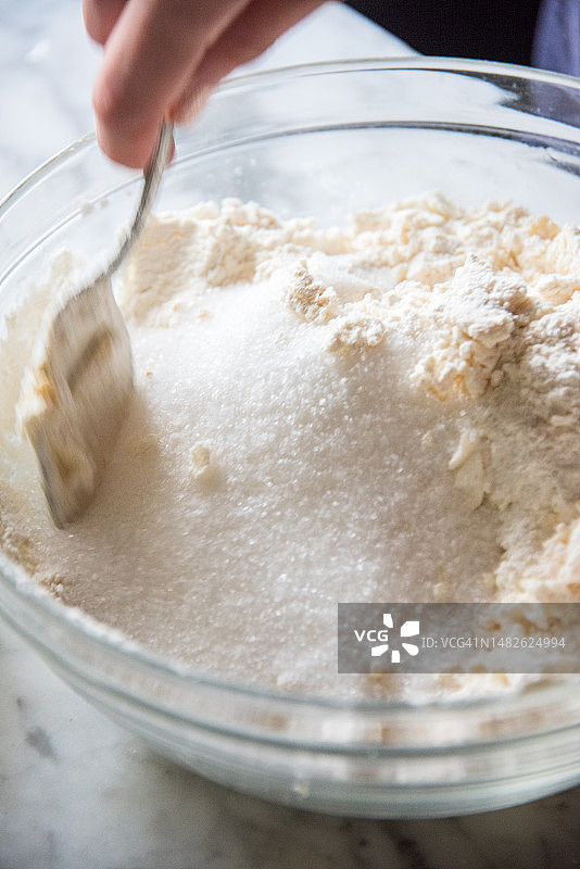 用叉子在玻璃碗中混合糖、面粉和鸡蛋图片素材