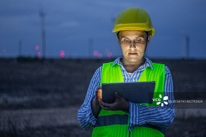 怀孕的风能工程师在风力发电场工作到很晚图片素材
