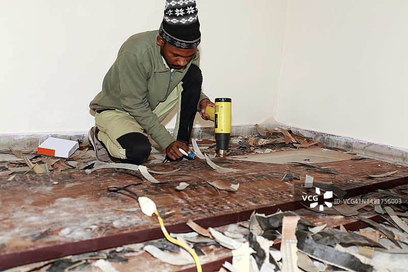 木匠用刮刀和热风枪去除木头上的旧清漆图片素材