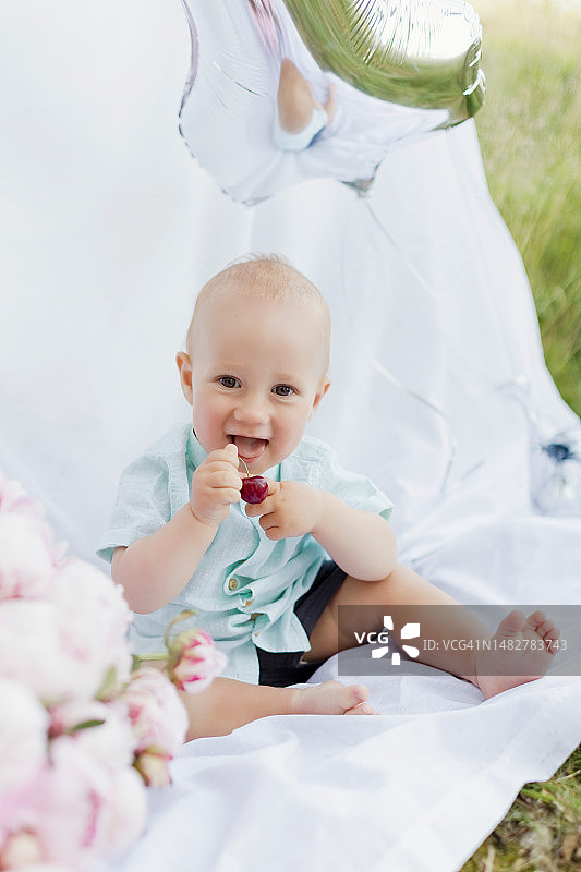 坐在户外牡丹花附近的白人男孩图片素材