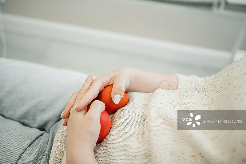 躺在美容椅上，手中拿着抗压球的中年妇女特写图片素材