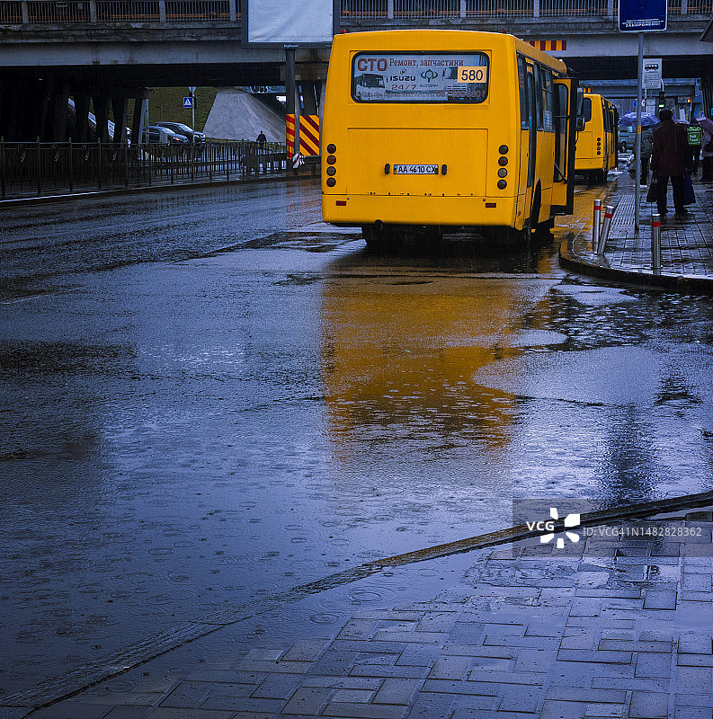 雨中行驶的黄色公共汽车图片素材