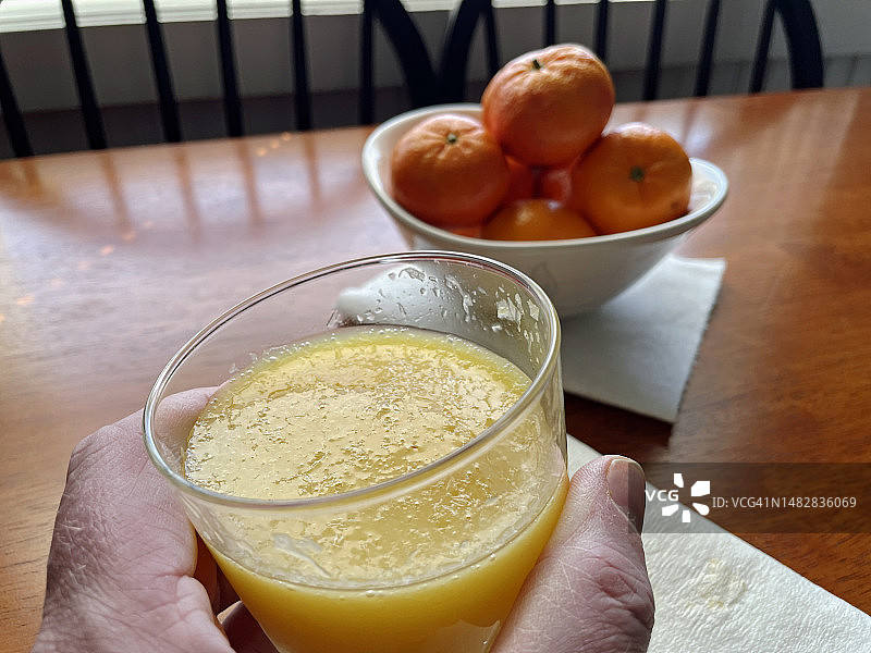 手持一杯橙汁，背景是橘子图片素材