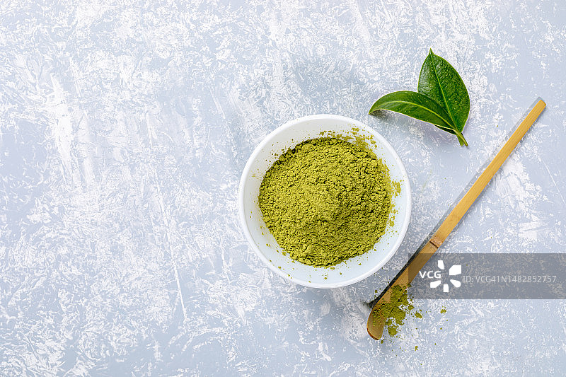 白色碗里的亚洲抹茶茶粉、竹勺和茶叶图片素材