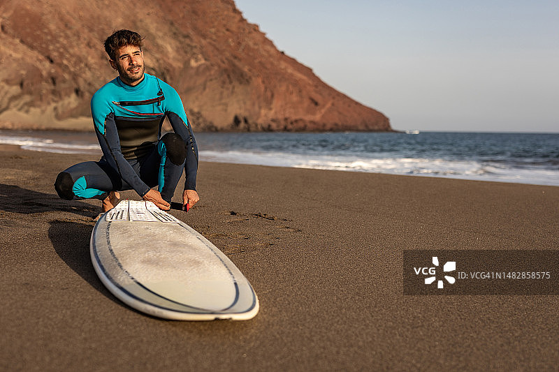 在海滩上拿着冲浪板的微笑青年图片素材