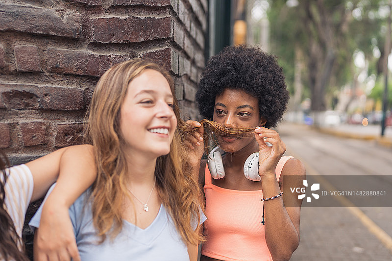 在户外与朋友的头发开玩笑的非洲女人图片素材