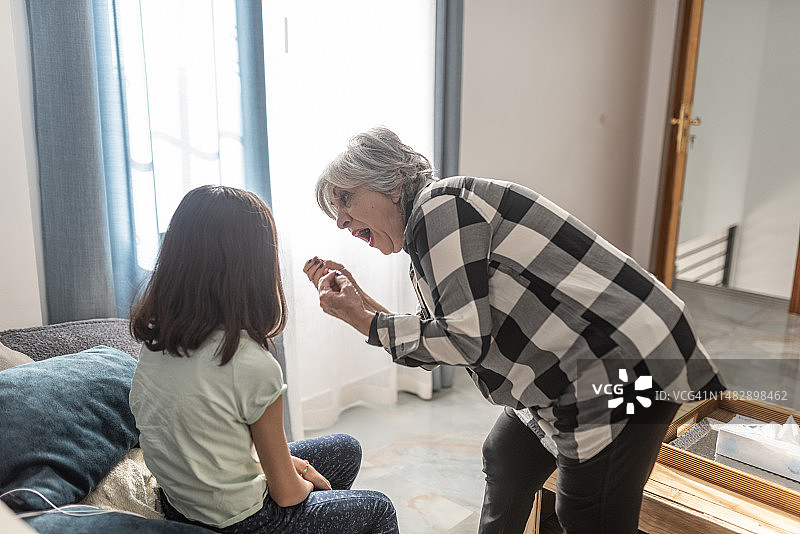 奶奶在房子的客厅里责备孙女并安慰她图片素材