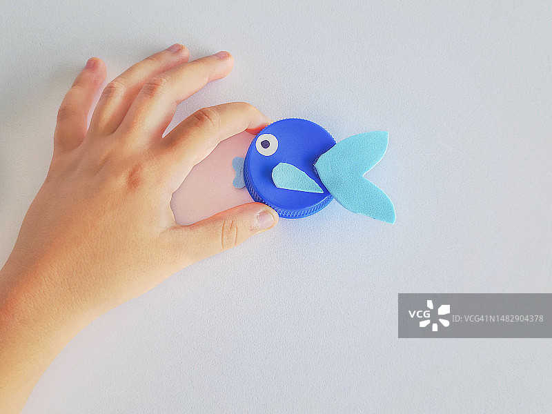 孩子的手拿着用回收材料制作的动物模型俯视图图片素材