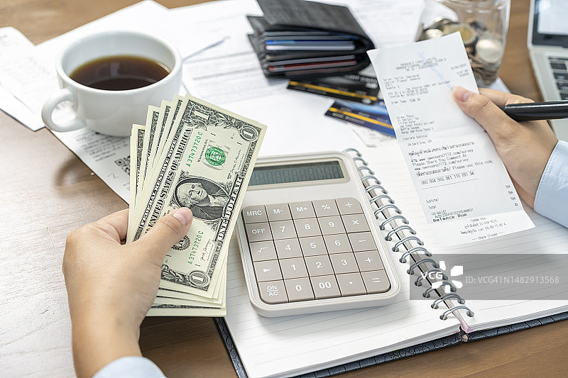手持发票和剩余的钱，每月预算概念图片素材