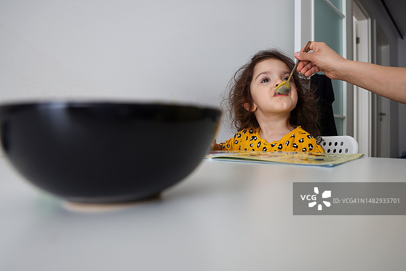 母亲用勺子喂小女孩图片素材