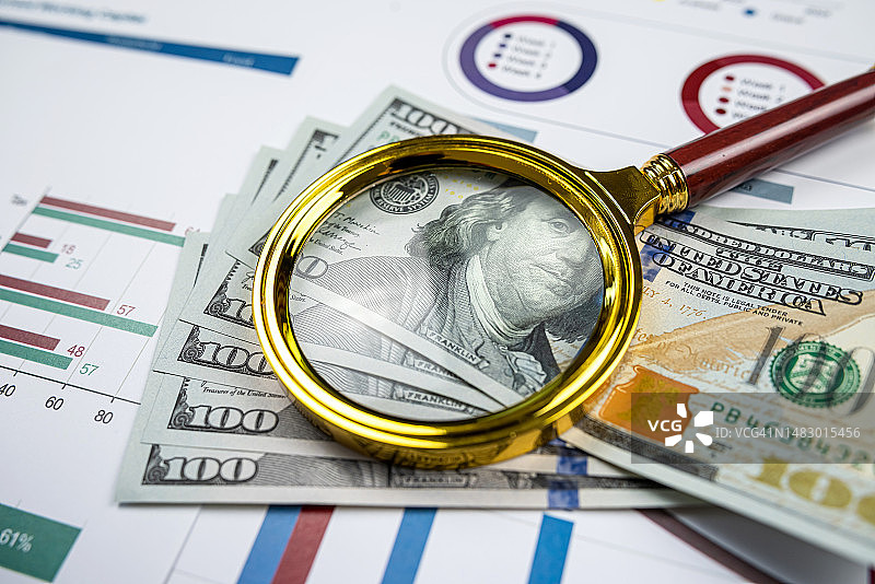 放大镜下的美元与商业图表图片素材
