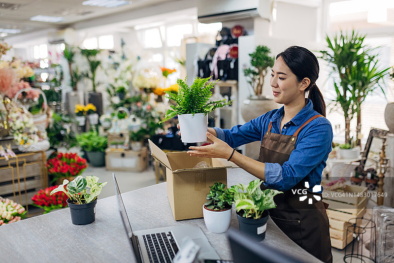 花店店员在花店柜台上将花盆装入纸箱图片素材