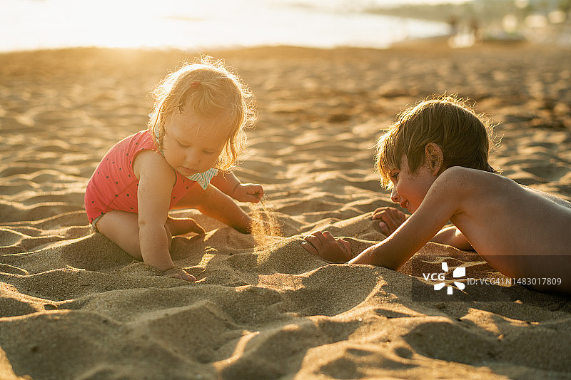 快乐的兄妹在海滩上玩沙子图片素材