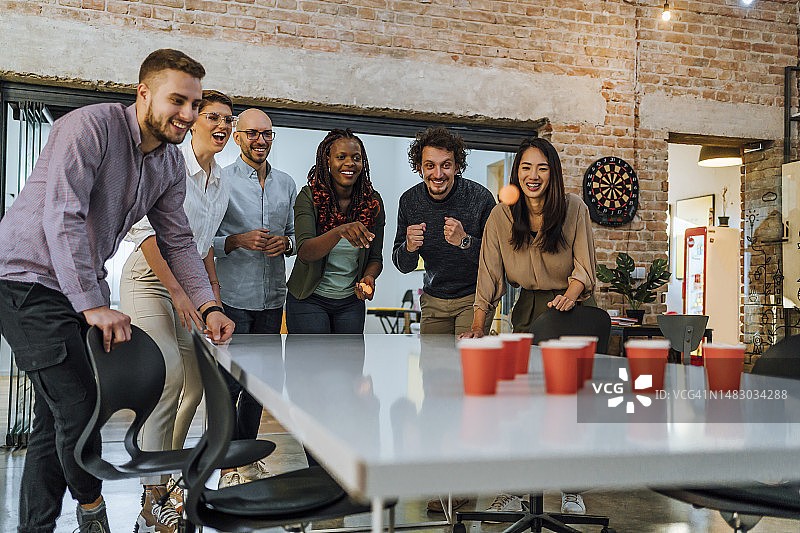 在办公室玩啤酒乒乓球的年轻同事图片素材