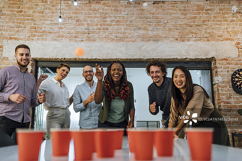 在办公室玩啤酒乒乓球的年轻同事图片素材