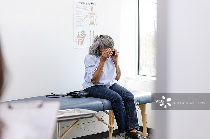 中年妇女一手扶头，一边打电话图片素材