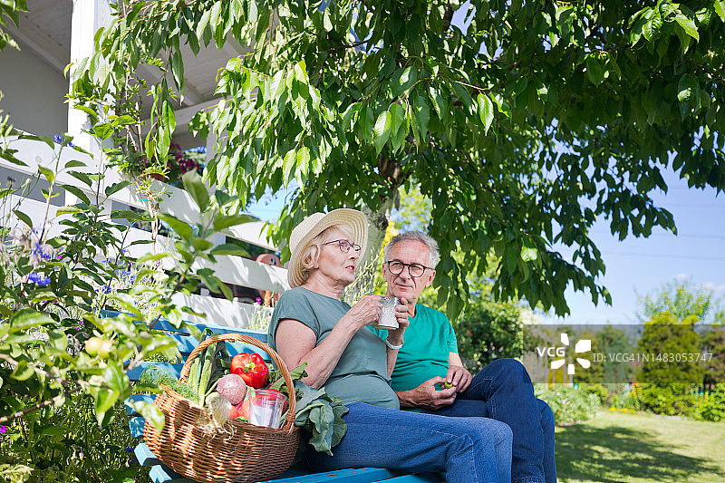 年长的女人在后院的长椅上与男人交谈时喝饮料图片素材