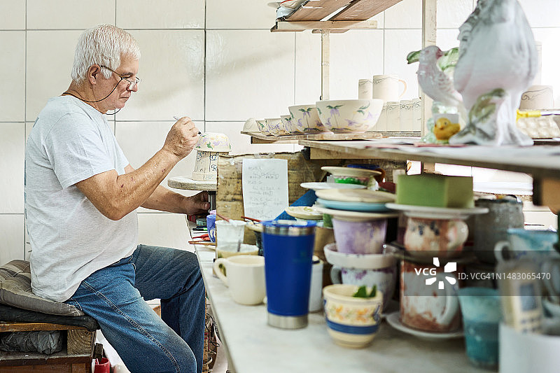 在陶瓷厂工作的年长工人在碗上绘制花卉图案图片素材