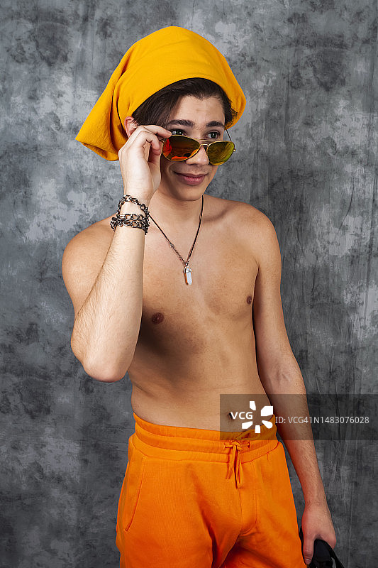 在炎热的夏日，裸着上身，穿着亮橙色短裤的英俊年轻男子 позирует портрет图片素材