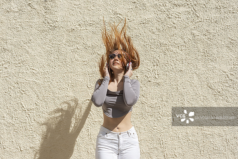 戴着太阳镜和耳机摇头晃脑的年轻女子图片素材