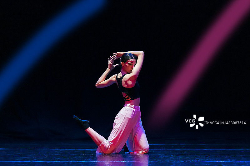 少女在舞台上跳着现代舞，灯光绚丽图片素材