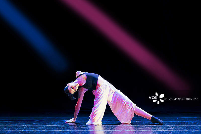 少女在舞台上跳着现代舞，灯光绚丽图片素材