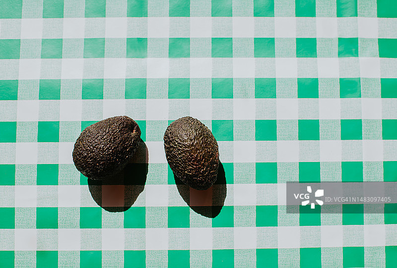 绿色格子桌布上两个成熟牛油果的明亮图案图片素材
