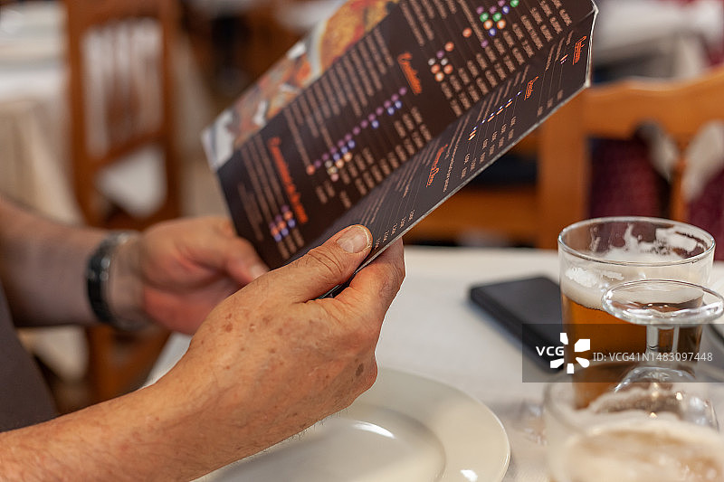 身份不明的男人坐在餐厅餐桌旁查看菜单图片素材