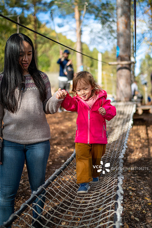 妈妈帮助孩子过绳索桥图片素材