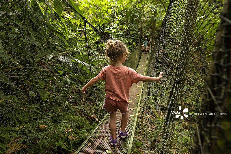 年轻女孩在哥斯达黎加丛林中徒步吊桥图片素材