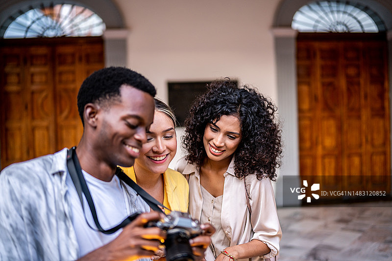 年轻的朋友们在户外看相机里拍摄的照片图片素材