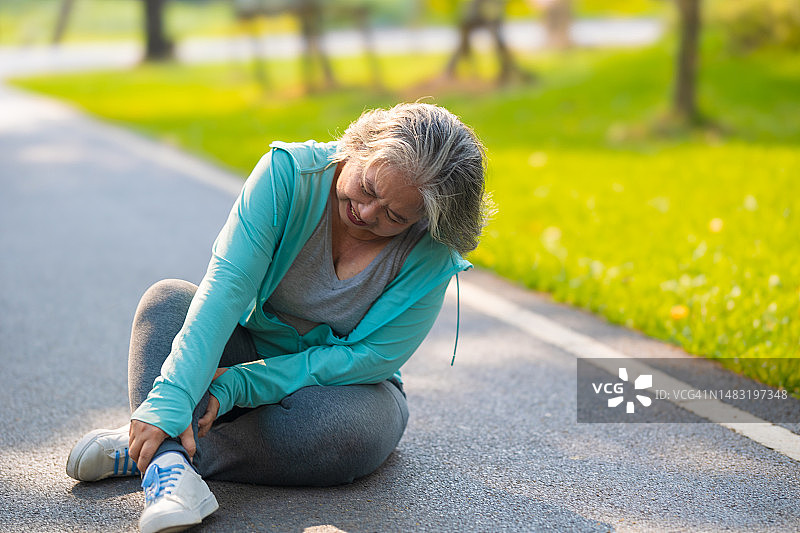 亚洲老年女性在公园锻炼时腿部疼痛图片素材