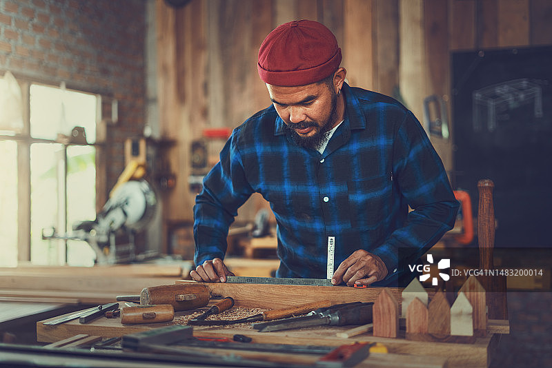 年轻木匠在他的工作台上测量木材图片素材